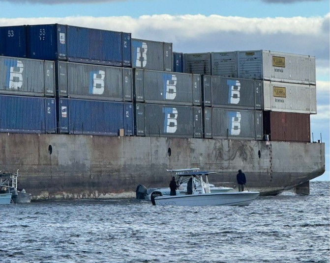 Barge Brooklyn Bridge aground with small craft alongside. 