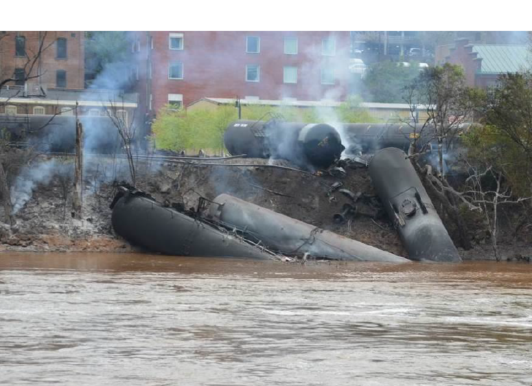 Smoldering, derailed tanks cars on the bank of the James River.