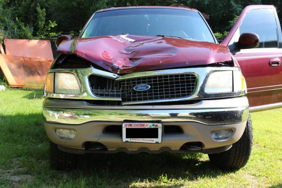 Photo of front of SUV showing contact damage to hood, grille, and bumper.
