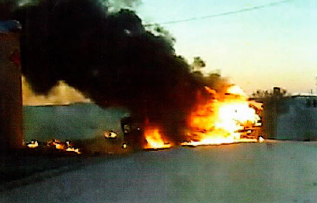 Burning school bus (right side) in still photograph captured from body camera video.