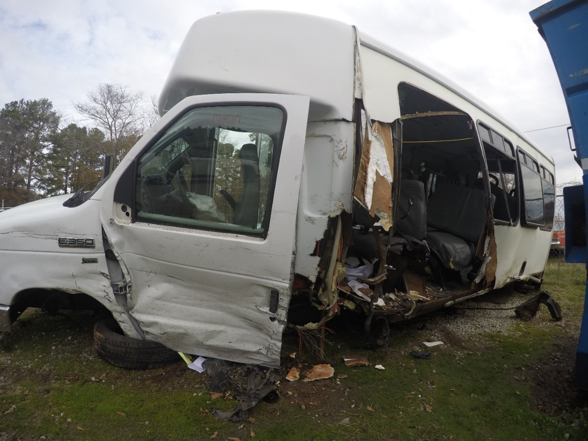 Wide-angle-lens photo of the crash-involved bus, with damage visible to the left side beginning at the front wheel.